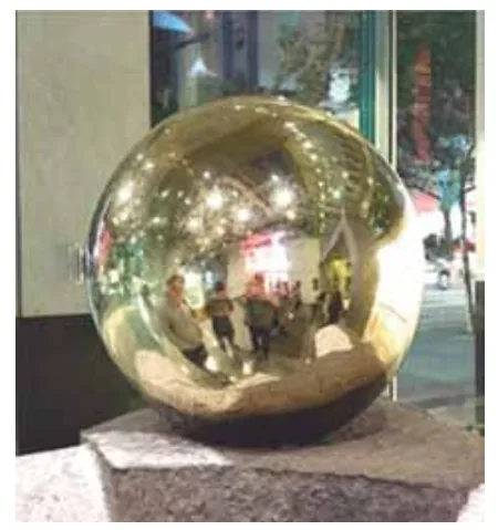 Esfera metálica polida e refletora exibindo reflexo do ambiente ao redor
