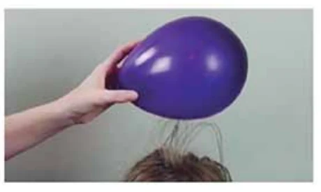 Balão eletrizado atraindo os cabelos de uma criança