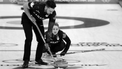 Jogadores varrendo a pista de curling à frente da pedra
