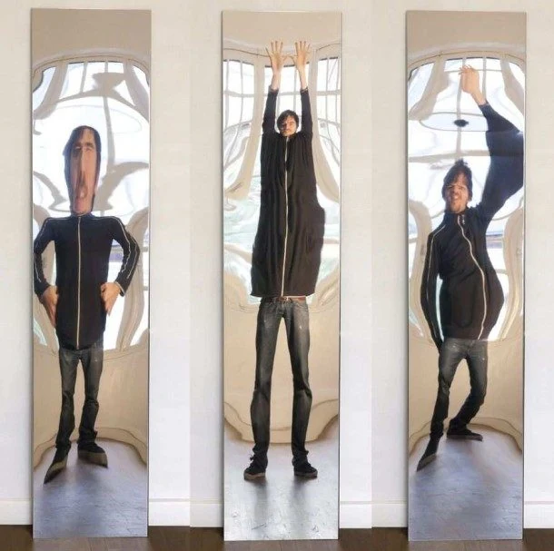 Três reflexos distorcidos de uma mesma pessoa em espelhos curvos de uma casa de espelhos