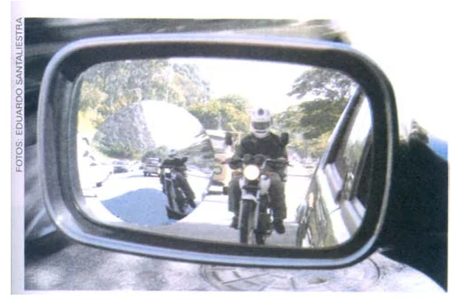 Fotografia do espelho retrovisor lateral de um carro, em que se veem motocicletas atrás do veículo em um campo visual amplo