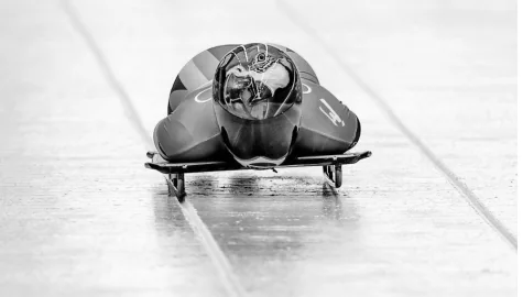 Atleta de skeleton descendo uma pista de gelo
