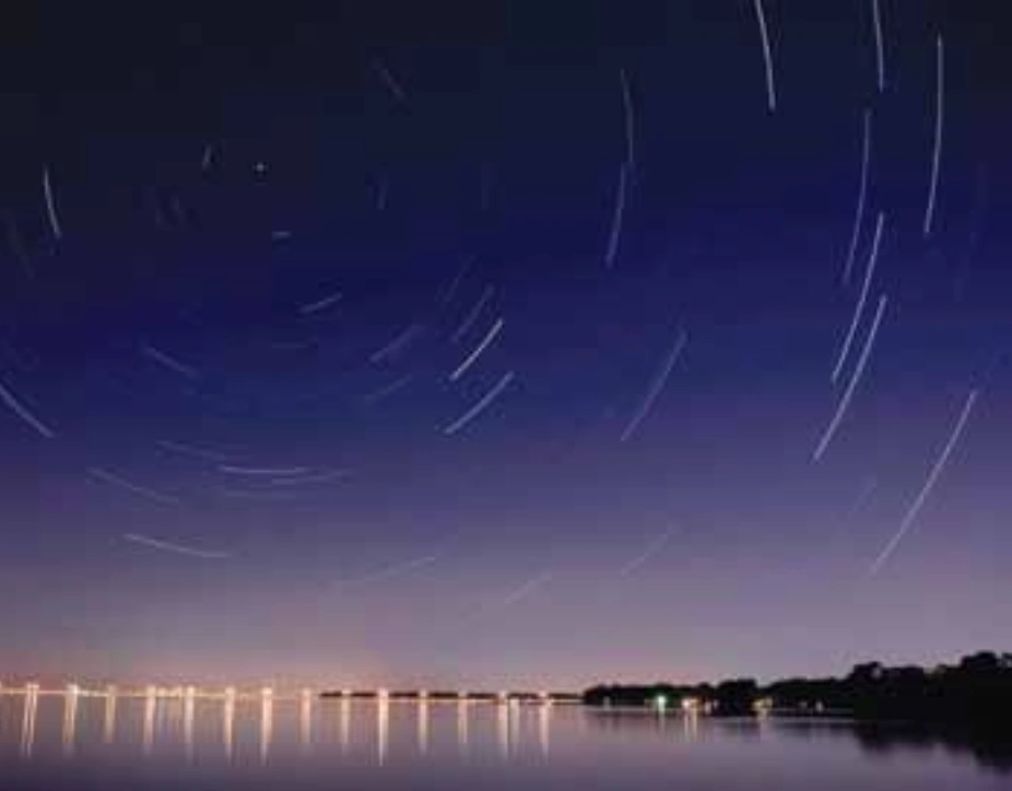 Fotografia de longa exposição do céu noturno mostrando rastros aparentes das estrelas