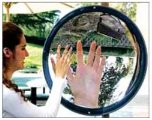 Fotografia de uma mulher com as mãos diante de um espelho circular; a imagem das mãos aparece no espelho.