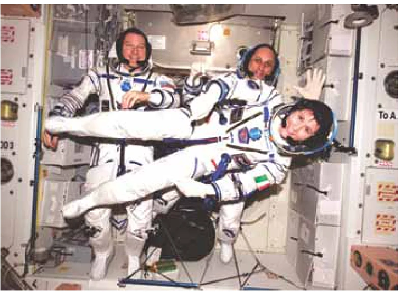 Três astronautas flutuando no interior da Estação Espacial Internacional
