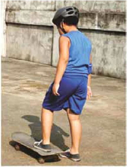 Garoto de capacete apoiando um pé sobre um skate em uma superfície plana