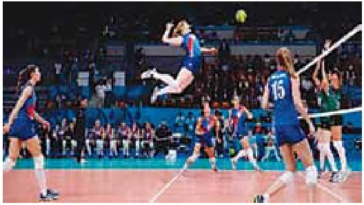 Atleta de voleibol no ar, no ponto mais alto do salto, golpeando a bola durante uma partida