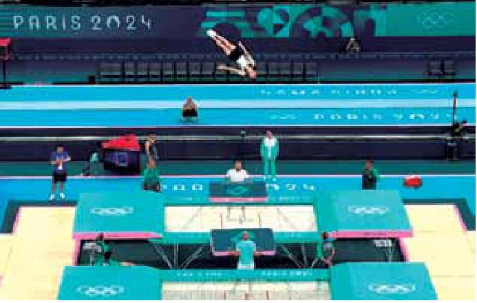 Atleta de trampolim no ar, acima da cama elástica, durante competição nos Jogos Olímpicos de Paris 2024